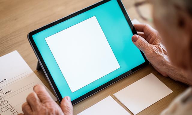 Close-up of a senior preparing for a Zoom call with a checklist on a table