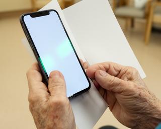 Senior learning smartphone essentials, practising messaging with large print guides